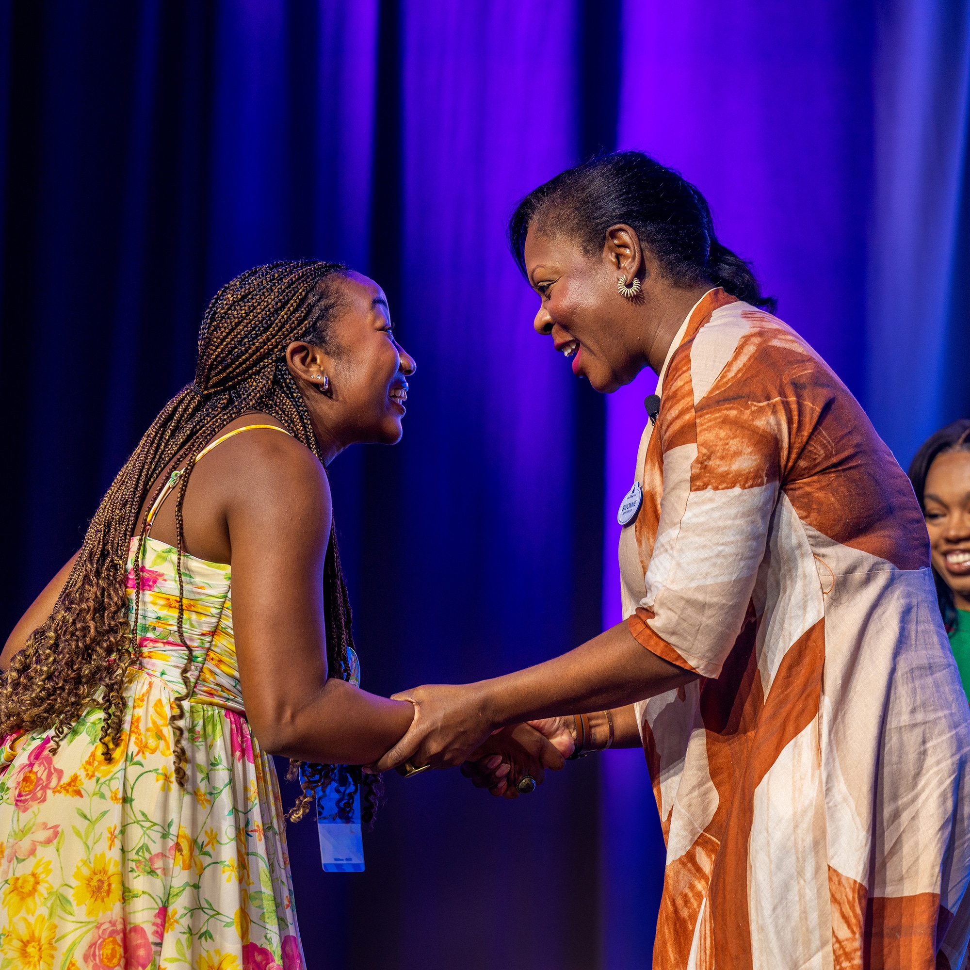 A woman shaking hands with a young girl while standing on stage