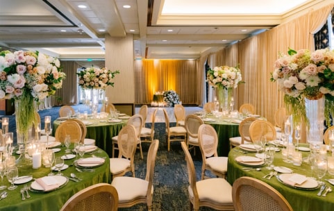 Reception room with dining tables topped with tall floral arrangements 