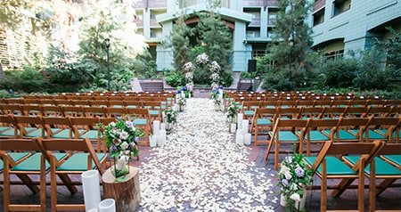 Two sections of chairs pointed towards a flower adorned altar and separated by an aisle strewn with rose petals