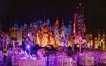 Tables and chairs decorated with flowers and set up in front of ‘it’s a small world’ in Disneyland Park