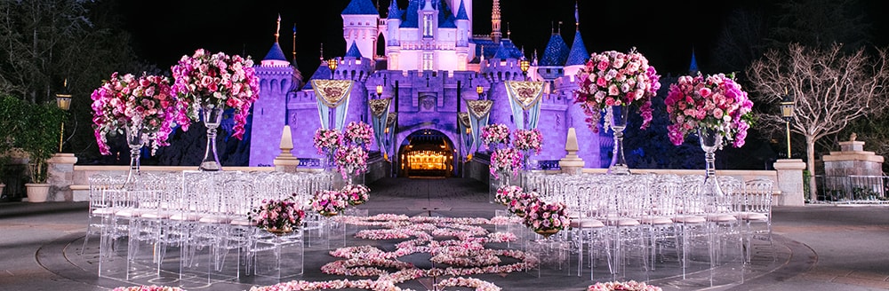 Chairs, flowers and an aisle of petals ready for a wedding ceremony in front of Sleeping Beauty Castle