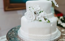 A two-tiered wedding cake decorated with fondant flower blossoms, made by Disney bakers