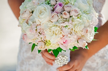 A bride holding a bouquet of flowers adorned with pearls