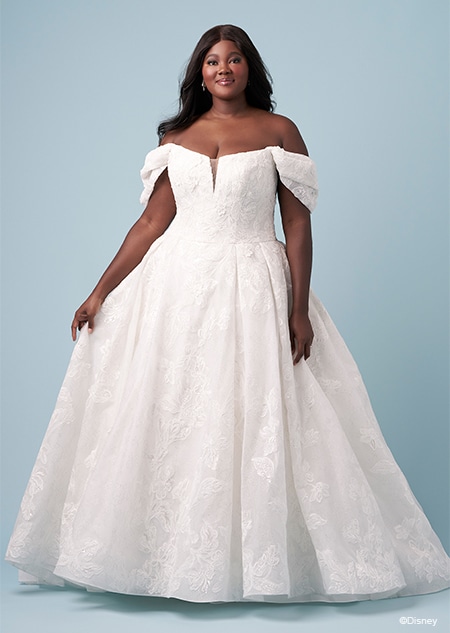 A bride wearing an Aurora inspired A line wedding gown featuring embroidery, an illusion neckline and off the shoulder sleeves