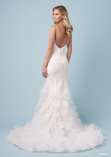 The back of a bride wearing an Ariel inspired trumpet wedding gown featuring beading, an exposed back and a ruffled train