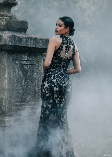 A woman posing by a stone structure with her back turned wearing a fitted gown with intricate lace details A woman posing by a stone structure with her back turned wearing a fitted gown with intricate lace details