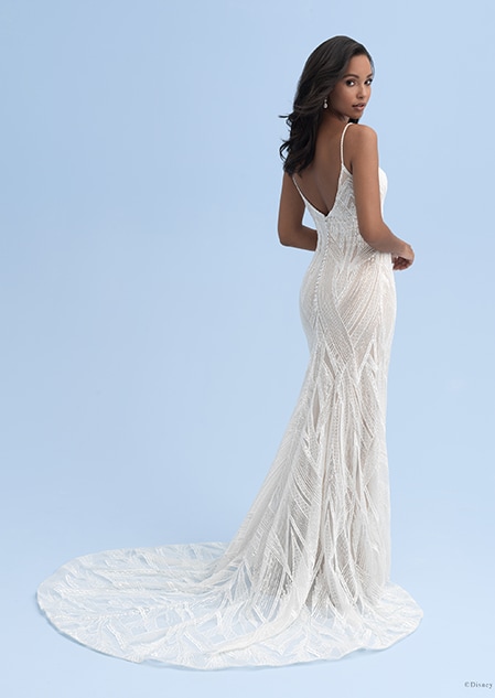 A woman looks over her shoulder while wearing a wedding dress with skinny straps and a small train A woman looks over her shoulder while wearing a wedding dress with skinny straps and a small train