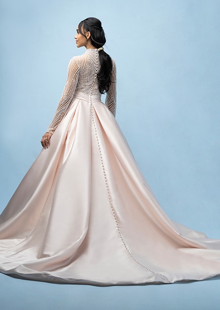 The back of a bride wearing a Jasmine inspired ball gown featuring a train and a sheer beaded bodice with long sleeves
