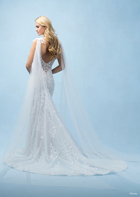 The back of a bride wearing a Rapunzel inspired sheath gown featuring a low back, lace detail, a train and shoulder trains