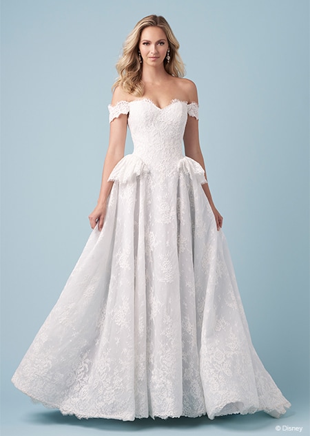 A bride wearing a Cinderella inspired A line gown featuring off the shoulder sleeves, a sweetheart neckline and short panniers on the hips