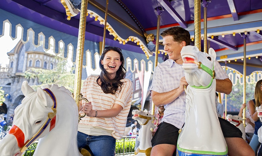 A couple smiling while riding on horses at King Arthur Carrousel