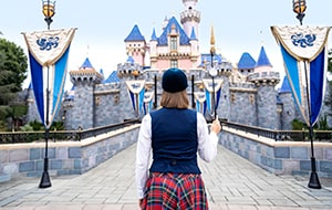 A VIP Tour guide holding up a guide pole as she walks down the bridge in front of Sleeping Beauty Castle