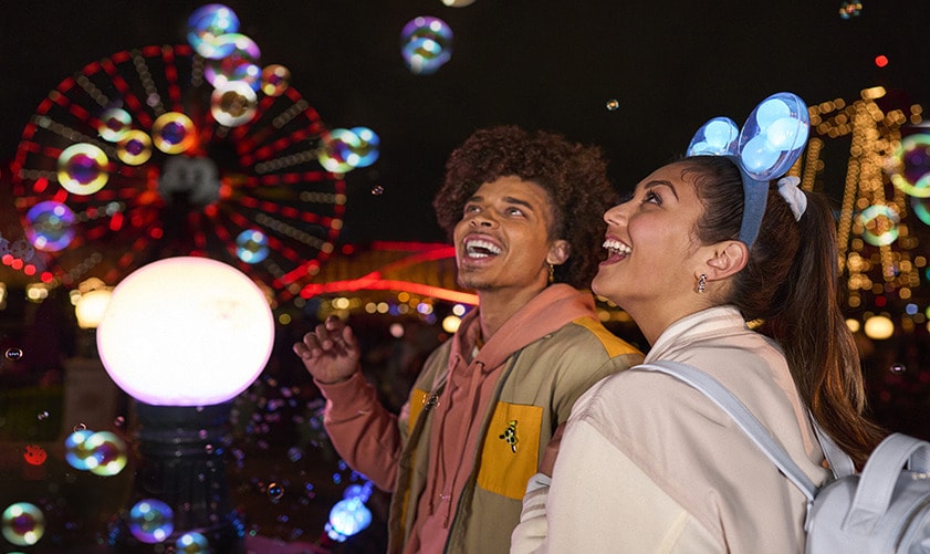 Guests smiling while surrounded by bubbles at the World of Color Dessert Party