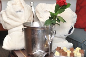 Two bathrobes, 2 champagne glasses, an assortment of chocolates and a champagne bucket containing a bottle of champagne and a rose