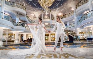 Two brides dancing on the stage of the Grand Hall on the Disney Wish