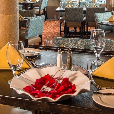 Table settings and a bowl containing rose petals and a glass slipper on a dining table at Cinderella’s Royal Table