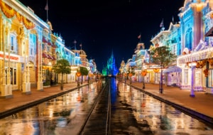 Main Street, USA lit up at night with Cinderella Castle in the distance