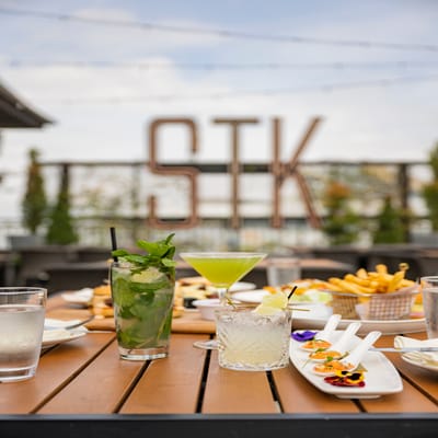 A patio dining table with appetizers, dishes and cocktails at STK Steakhouse