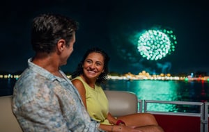 A couple smiling at each other while riding on a fireworks cruise at World Showcase Lagoon