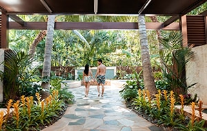 A couple walking towards 2 outdoor pools at Laniwai, A Disney Spa