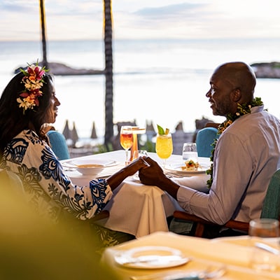 A couple holding hands while dining on the patio at Ama Ama, Contemporary Island Cooking
