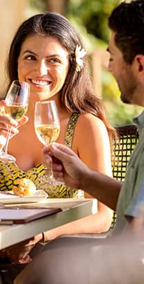 A man and woman toast one another with glasses of white wine