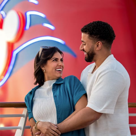 A man and a woman smiling and looking at each other on the top deck of a Disney Cruise Line ship A man and a woman smiling and looking at each other on the top deck of a Disney Cruise Line ship