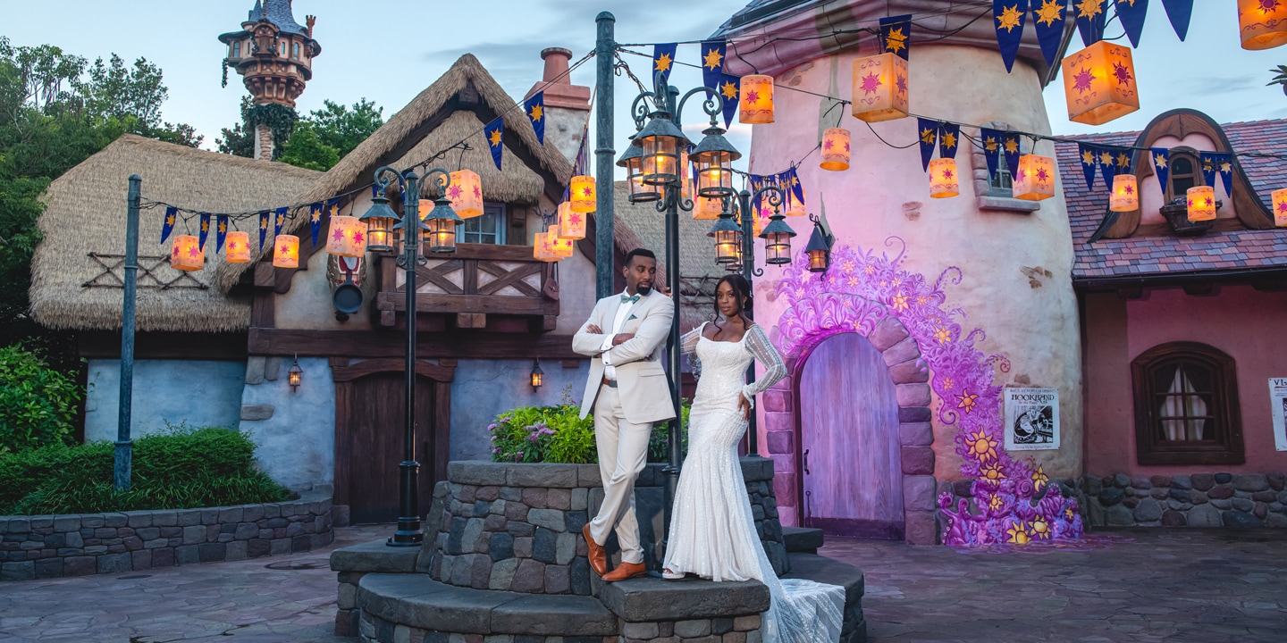 A wedding couple posing amid whimsical Tangled themed lanterns and buildings at Magic Kingdom park