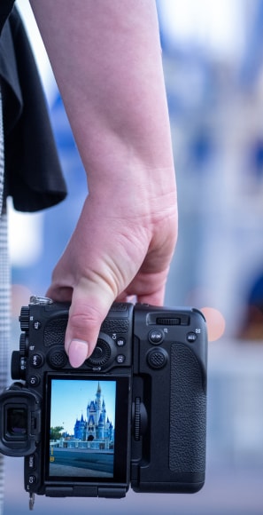 A photographer's hand holding a camera displaying Cinderella Castle on its screen at Magic Kingdom park A photographer's hand holding a camera displaying Cinderella Castle on its screen at Magic Kingdom park