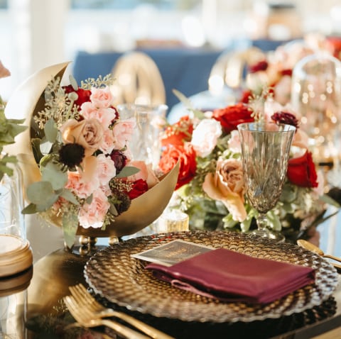 Wedding reception table setting with floral centerpieces and a decorative plate at Sea Breeze Point Wedding reception table setting with floral centerpieces and a decorative plate at Sea Breeze Point