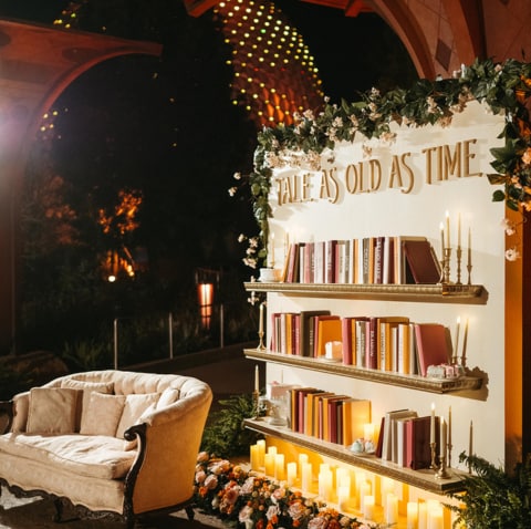A bookshelf with a sign that says, ‘Tale as old as time’ in a room with floral decorations A bookshelf with a sign that says, ‘Tale as old as time’ in a room with floral decorations