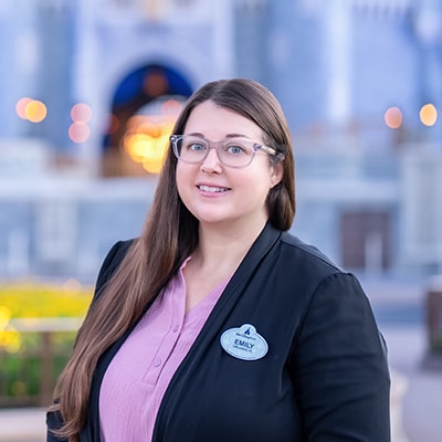 A Disney Cast Member standing with Cinderella Castle in the distance