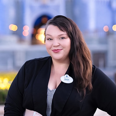 A Disney Cast Member standing with Cinderella Castle in the distance