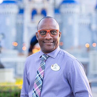 A Disney Cast Member standing with Cinderella Castle in the distance