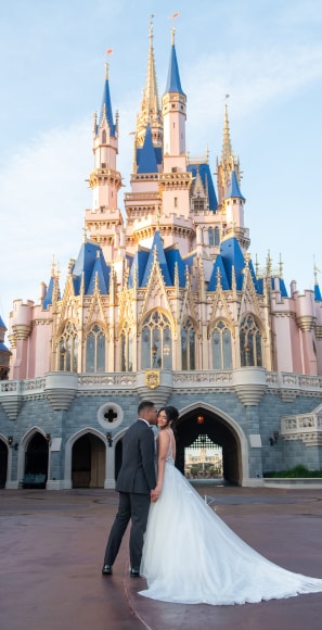 A groom kissing his bride on the cheek next to Cinderella Castle at Magic Kingdom park A groom kissing his bride on the cheek next to Cinderella Castle at Magic Kingdom park