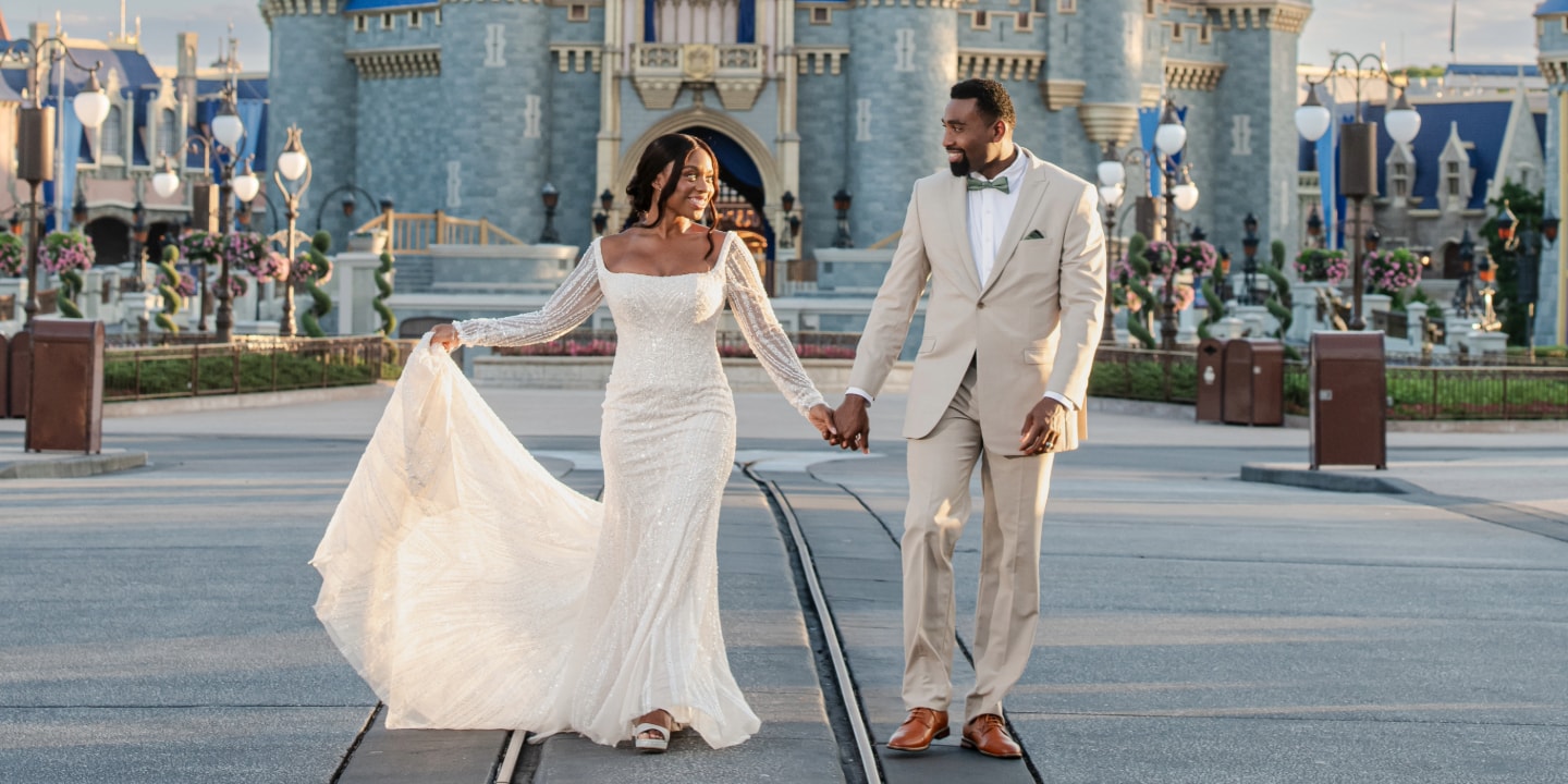A vow renewal couple walking hand in hand near Cinderella Castle at Magic Kingdom park