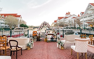 The patio at Disney’s Grand Floridian Resort and Spa, overlooking the marina, with chairs and love seats facing a floral wedding arch