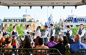 A bride and groom get married in front of a crowd of people in the train station overlooking Cinderella Castle