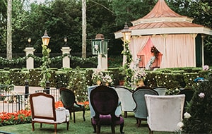Armchairs on a lawn in front of a hege and canopy decorated for a ceremony