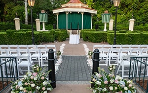 Chairs set up at a wedding venue in a garden with hedges, a canopy and floral arrangements at United Kingdom Courtyard Chairs set up at a wedding venue in a garden with hedges, a canopy and floral arrangements at United Kingdom Courtyard