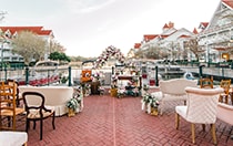 The patio at Disney’s Grand Floridian Resort and Spa, overlooking the marina, with chairs and love seats facing a floral wedding arch