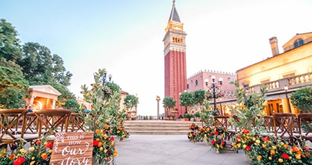 A courtyard decorated for a wedding ceremony near a tower and trees in Italy Plaza in Epcot