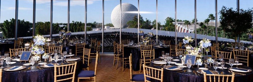 Circular tables arranged in a room with long clear windows showing a view of Spaceship Earth