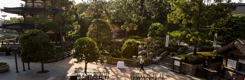 Flower petals scattered along an aisle near a large Japan-inspired building and many lush trees