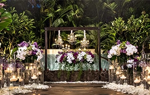 Several lit candles line an aisle along with several bouquets of flowers