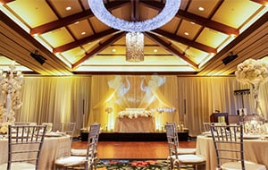 Round tables with elaborate floral centerpieces in a room with a dance floor