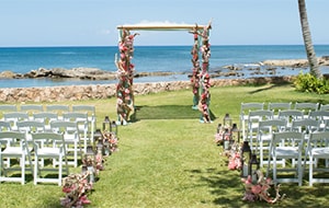 Folding chairs on both sides of an aisle leading towards an altar on a lawn by the ocean
