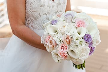 A bride holds a bouquet of roses and other flowers