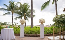 A table with candles and 2 flower stands grace a patio overlooking the ocean A table with candles and 2 flower stands grace a patio overlooking the ocean