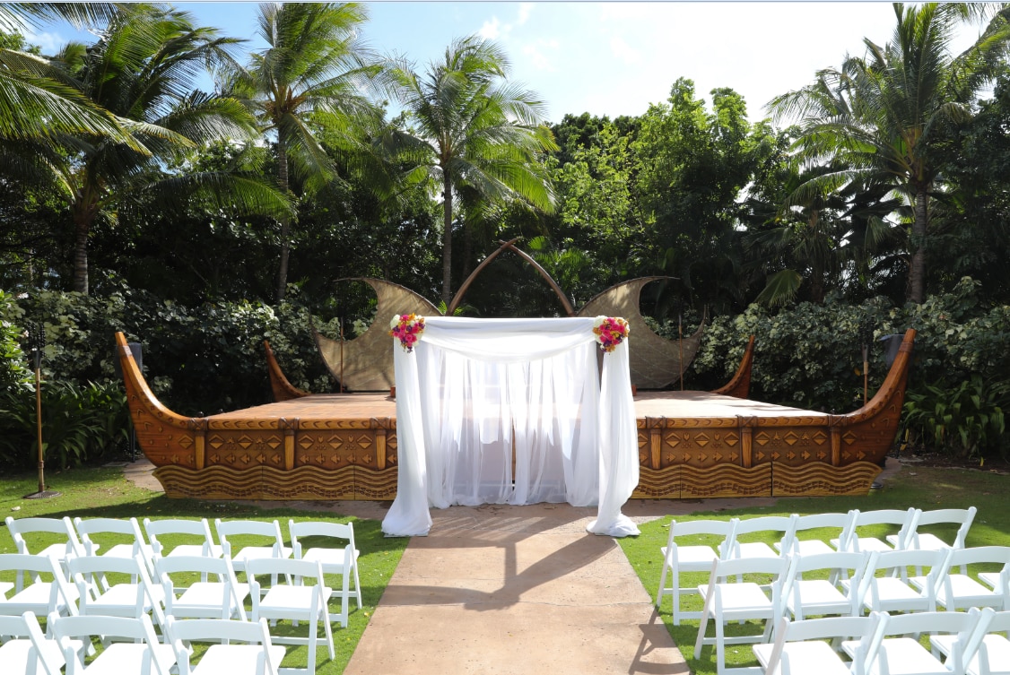 An altar arranged in front of a stage surrounded by lush trees
